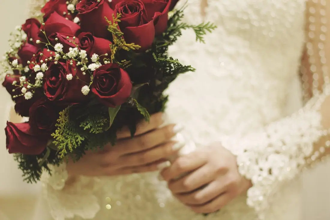 A bride holding a bouquet of red roses