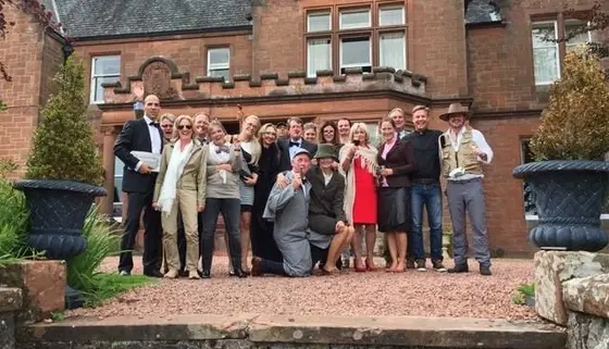 Guests in costume outside a red stone country house