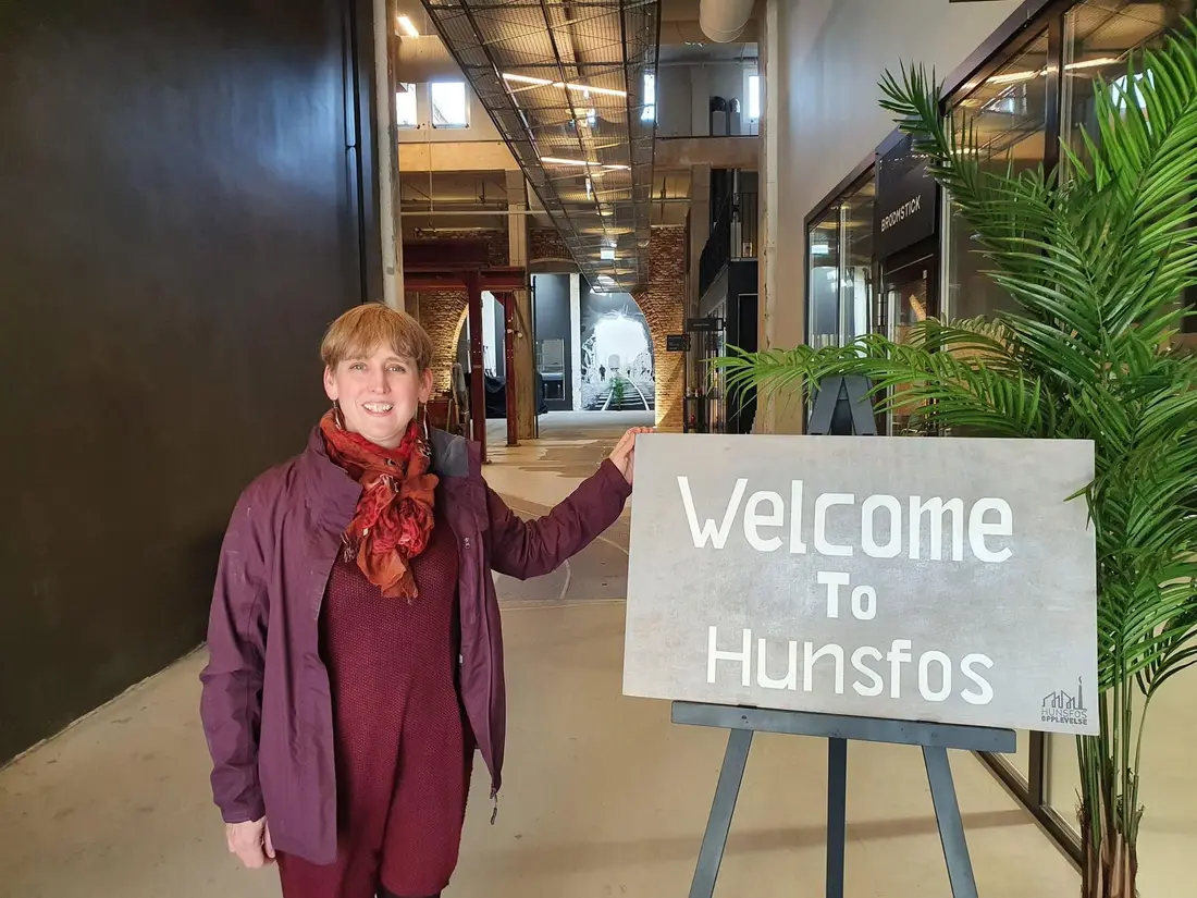 Jo from Red Herring Games beside a "Welcome to Hunsfos" sign at a launch event
