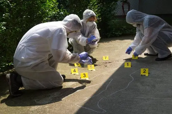 Forensic officers in white suits examining a crime scene