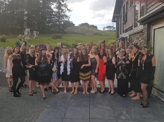 A hen party in 1920s costume outside a country house