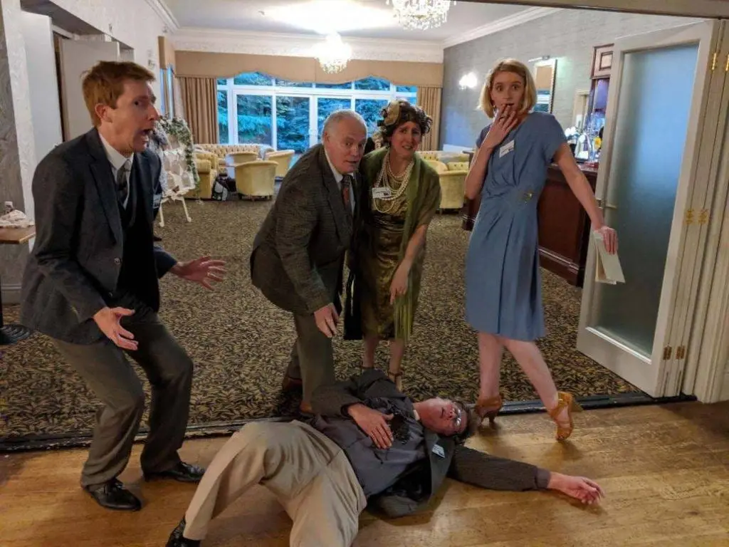 Actors playing out a murder scene, the victim on the floor