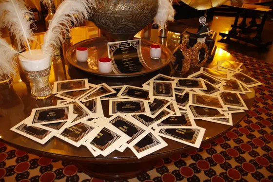 Murder mystery clue cards laid out on a table with feathers and candles