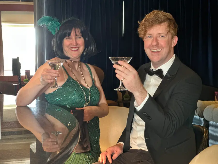Two guests in 1920s dress raising a toast at a murder mystery evening